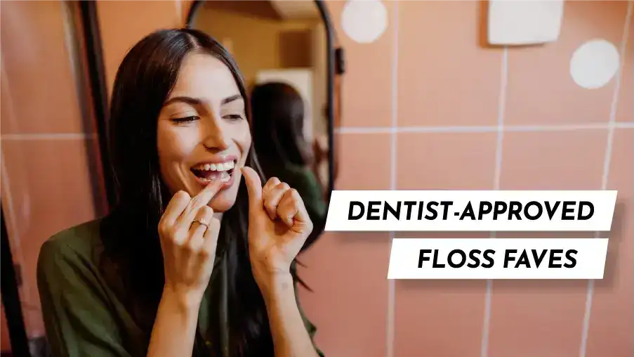 A woman flossing her teeth using one of Midtown Dental Group’s top dentist-recommended dental floss products, smiling in a clean, modern bathroom
