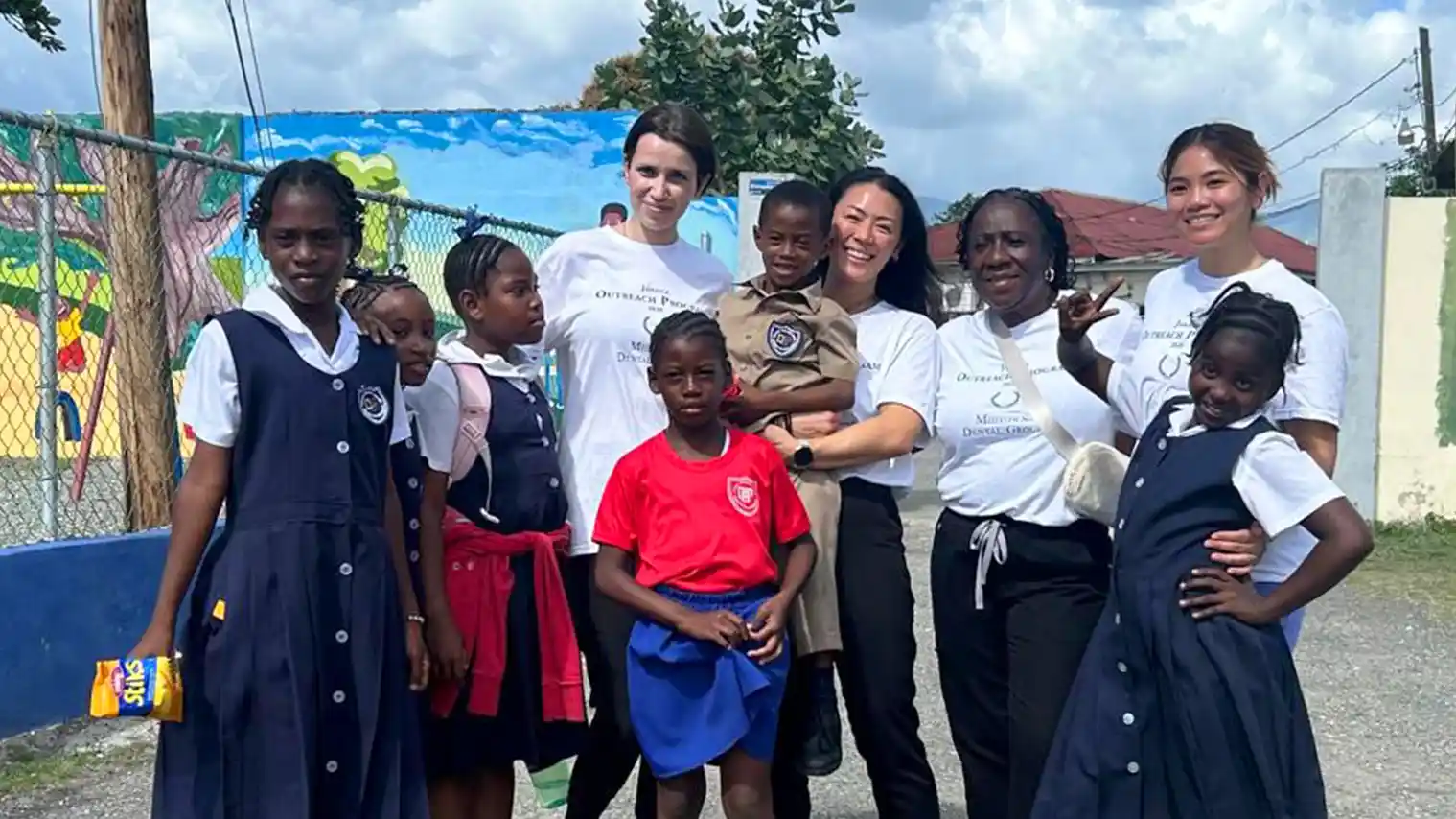 Midtown Dental Group team members posing with local children during their 2025 dental mission trip to Jamaica