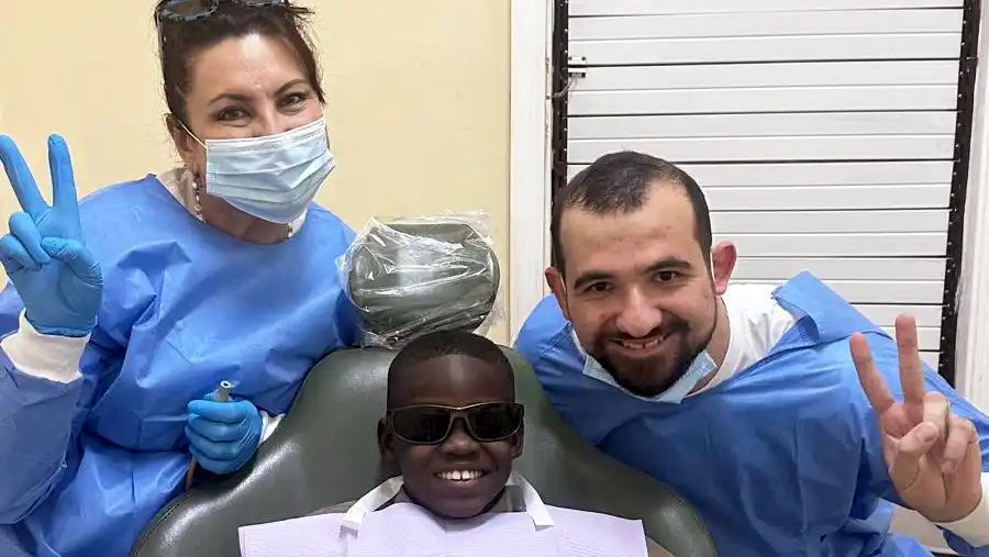 Two Midtown Dental Group team members provide a dental cleaning to a child during an MDG mission trip in Jamaica