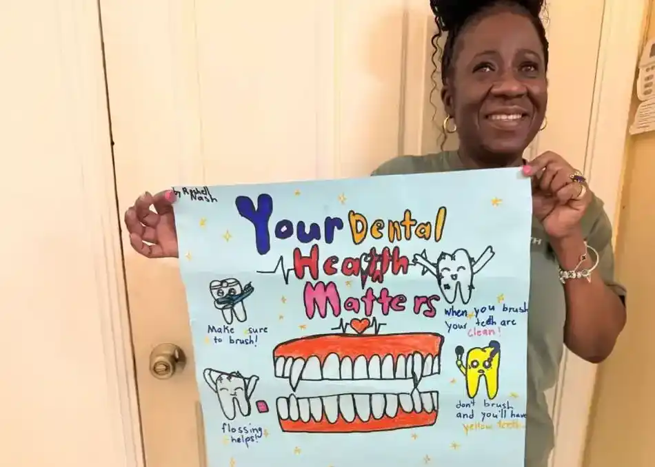 Violet smiles while holding a handmade poster created for her by children during the MDG mission trip in Jamaica